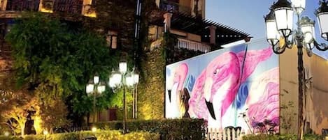 A courtyard with a fountain, seating areas, and a building with a large mural.