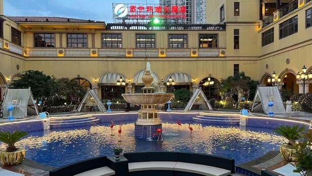 A hotel courtyard with a central fountain, a swimming pool, and a covered seating area. - Nanjing Suning Universal Hotel (Nanjing)