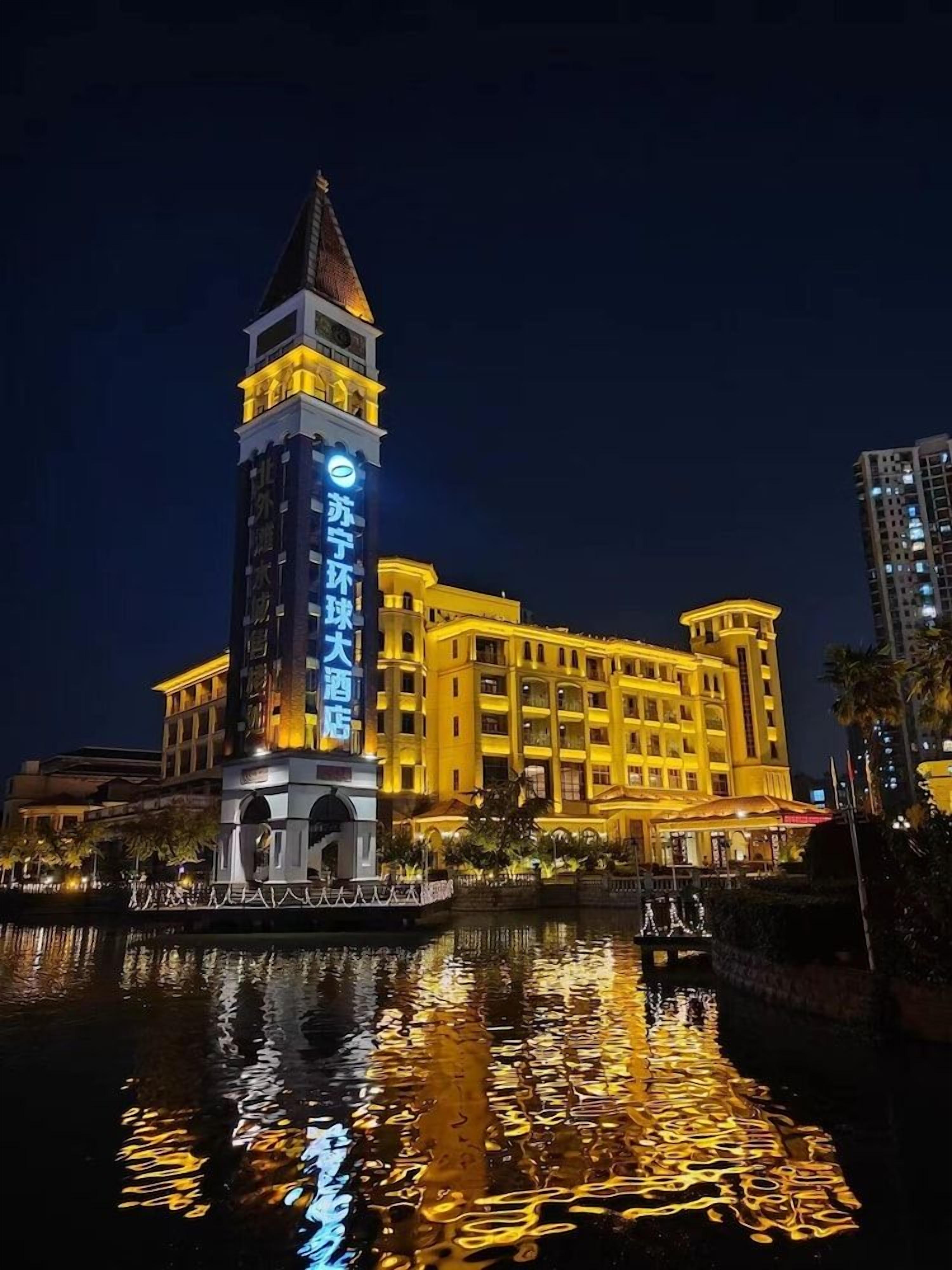 A hotel with a prominent tower and a reflection in the water.