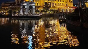 A hotel with a prominent tower and a reflection in the water. - Nanjing Suning Universal Hotel (Nanjing)
