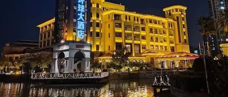 A hotel with a prominent tower and a reflection in the water.