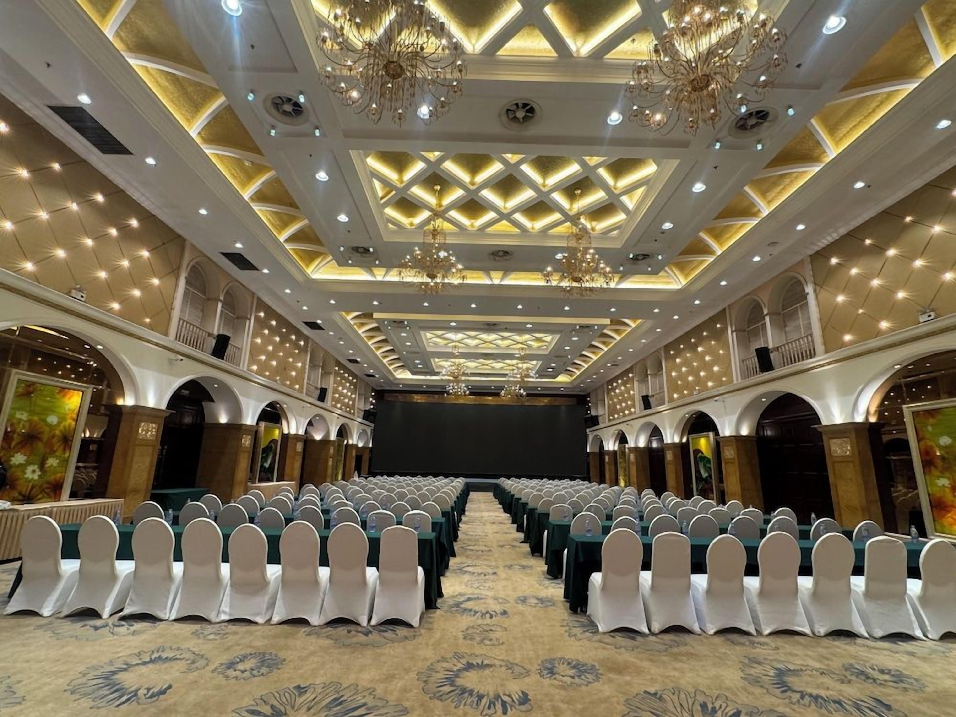Un salón de conferencias con filas de sillas, un escenario y candelabros.