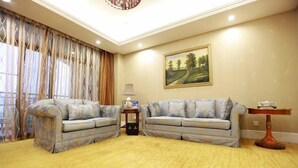A living room with two sofas, a lamp, a painting, and a table. - Nanjing Suning Universal Hotel (Nanjing)