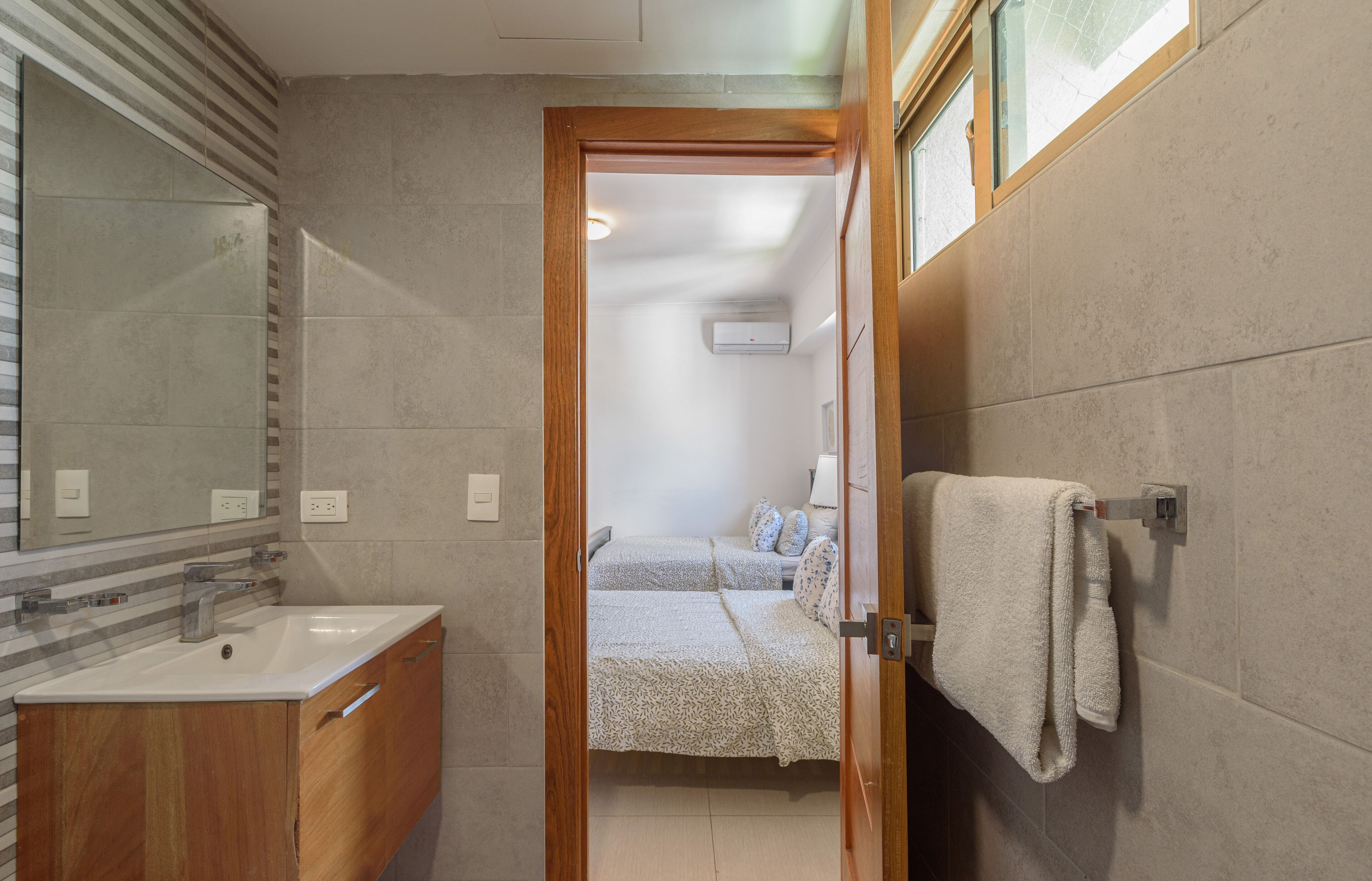 Un baño con tocador de madera, lavamanos y perchero para toallas.