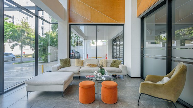 A modern interior with a sofa, ottomans, and a chair. - Amazing Harmony Apt 17FLR in LaJulia @Pool*Gym*Spa (Santo Domingo)