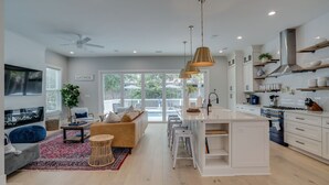 Une cuisine moderne avec des meubles blancs, un îlot central et un coin repas comprenant un canapé et des chaises.