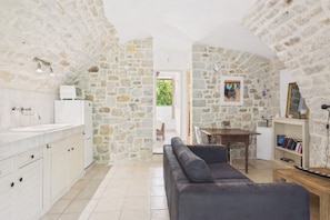 Une pièce chaleureuse avec un mur en pierre, un canapé, une table à manger et une bibliothèque.