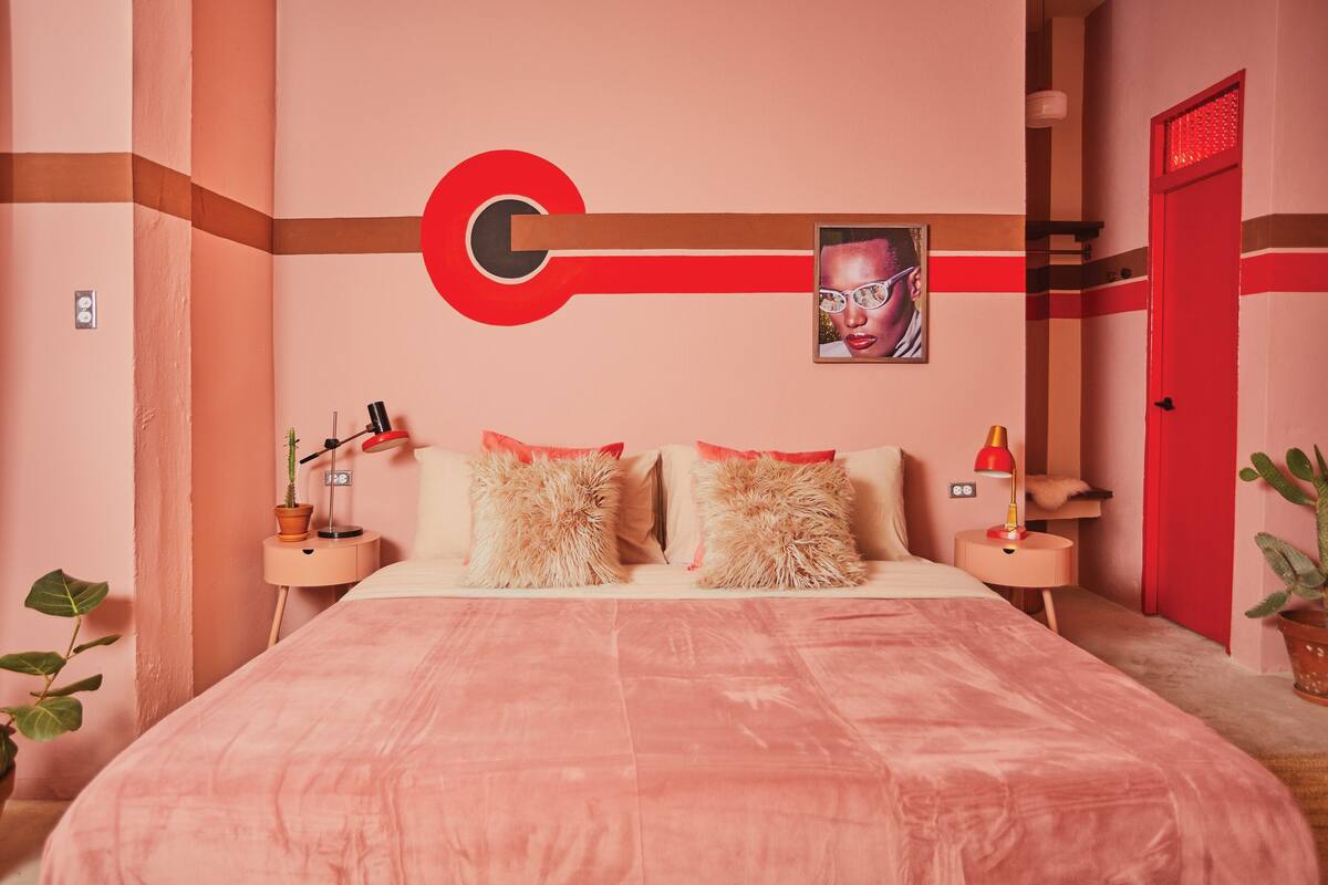 Ein Schlafzimmer mit einem großen Bett, zwei Nachttischen, einer roten Tür und einem Wandtresor.