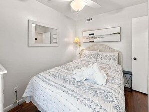 A bedroom with a bed, a bedside lamp, a mirror, and a door.