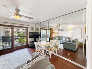 A spacious living area with a dining table, chairs, a sofa, and a television.