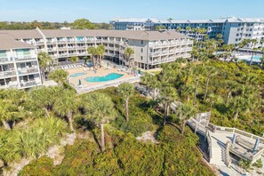 A resort with multiple buildings, a central pool area, and surrounding palm trees.