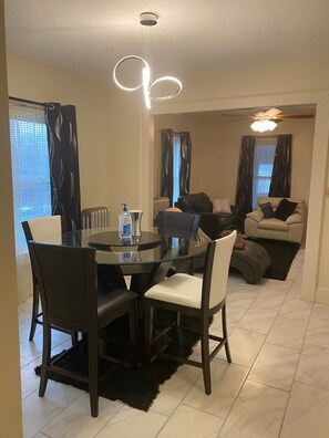 A modern living room with a glass dining table, dark chairs, a sofa, and a ceiling fan. - Two Families, up and Down Stairs, the 2nd Floor is the Vrbos Apartment (New Britain)