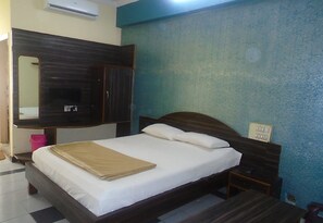 A bedroom with a bed, a wardrobe, a bedside table, and a wall-mounted air conditioner.