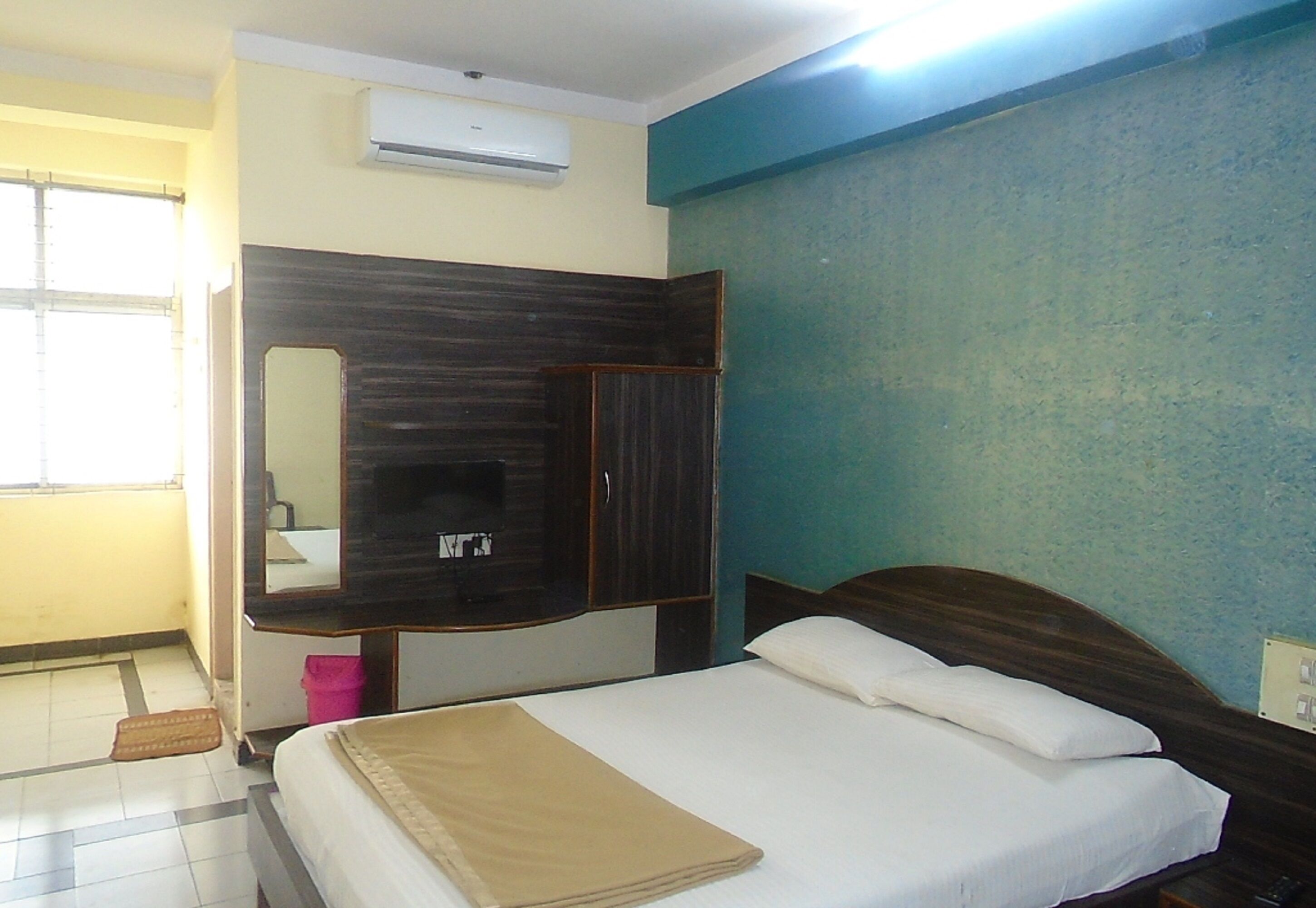 Una habitación de hotel con cama, armario, espejo y ventana.