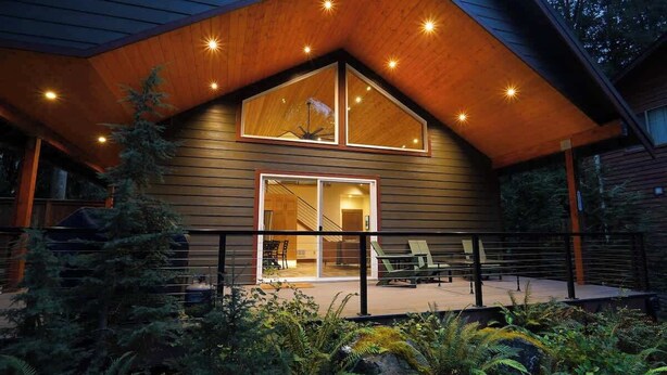 Une maison moderne avec un toit en pente, de grandes fenêtres et un patio couvert.