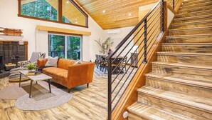 Un vaste espace de vie comprenant un escalier en bois, un canapé et un coin repas.