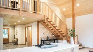 Una cucina moderna con una scala in legno, un'area pranzo e vista sull'esterno.