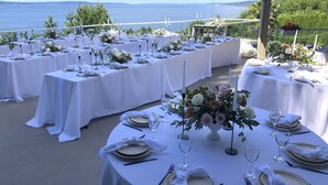 A series of round tables set up outdoors with white tablecloths, each adorned with a centerpiece of flowers and candles, overlooking a scenic view. - Peaceful Seattle Luxury Estate Romantic Seaview Guesthouse (Seattle)