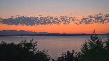 En stilla sjö vid solnedgången, med avlägsna berg och en klar himmel.