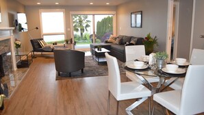 A modern living room with a sofa, chairs, a dining table set for four, and a fireplace. - Peaceful Seattle Luxury Estate Romantic Seaview Guesthouse (Seattle)