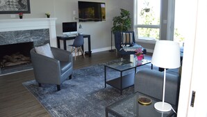 A living room with a fireplace, a television, a desk, and a comfortable seating area. - Peaceful Seattle Luxury Estate Romantic Seaview Guesthouse (Seattle)