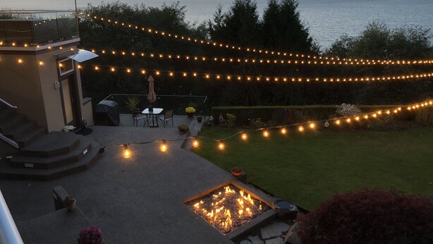 A patio with outdoor seating, string lights, and a fire pit. - Peaceful Seattle Luxury Estate Romantic Seaview Guesthouse (Seattle)