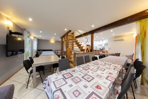 A modern hotel room with a large bed, a dining area, a kitchen, and a staircase.