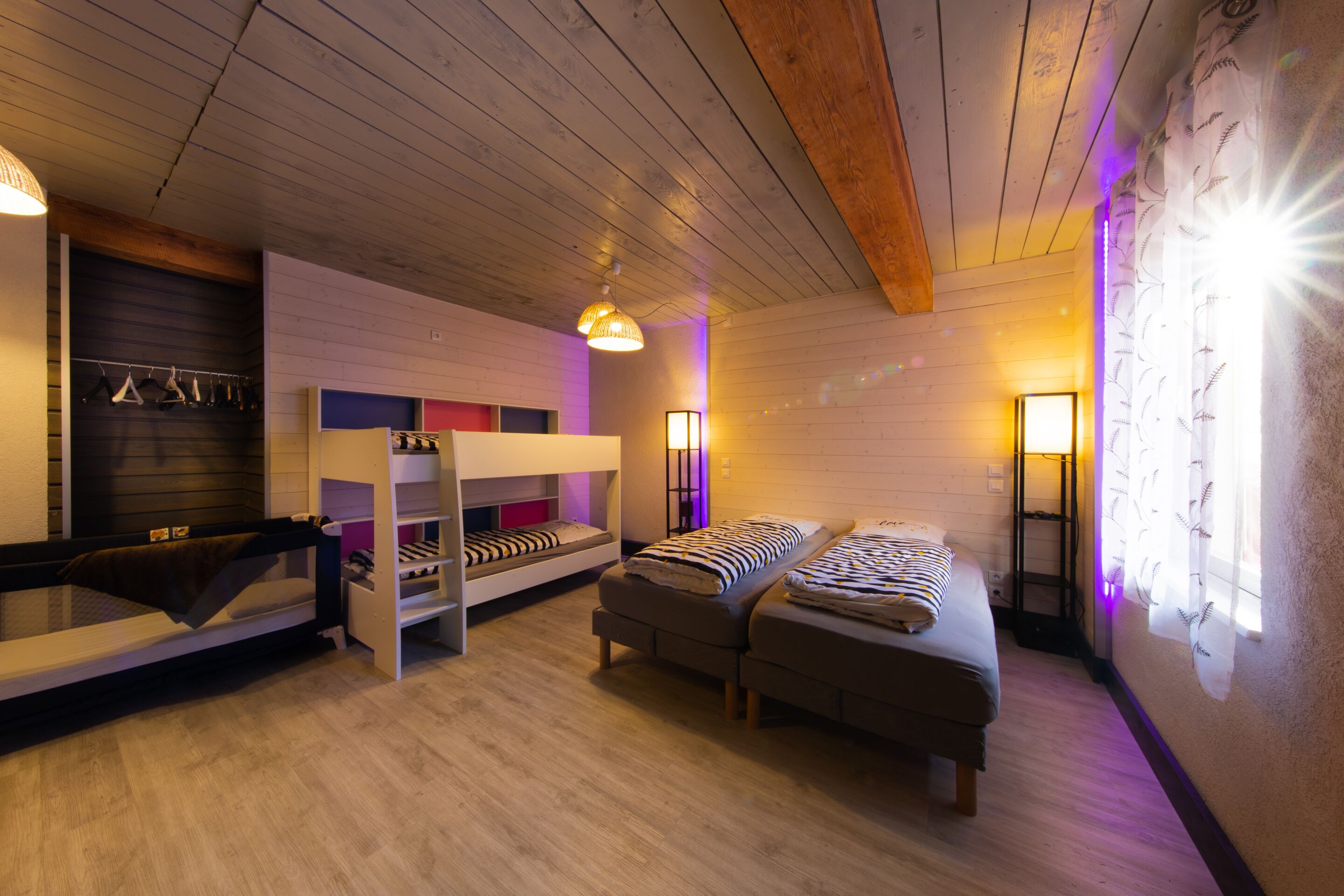 A room with bunk beds, a sofa, a hanging light fixture, and a wall-mounted lamp.