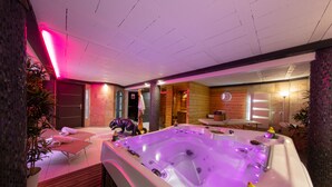 Een wellnessruimte met een jacuzzi, houten wanden en een receptiehoek.
