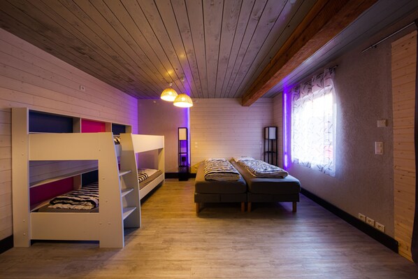 A room with bunk beds, a sofa, and a window with curtains.