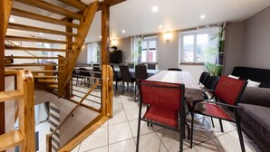 Een eetruimte met een houten trap, een tafel met stoelen en uitzicht op buiten.