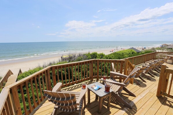 A wooden deck with outdoor seating overlooking a beach. - Sea Spirit OBX Dog Friendly Oceanfront HotTub (Corolla)