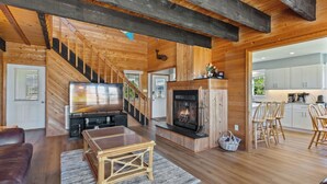 A spacious living room with a fireplace, a television, and a dining area with wooden chairs.