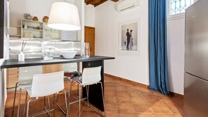 Una cucina con tavolo da pranzo, sedie, lampadario e frigorifero.