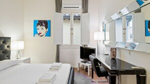 Una camera d'albergo con un letto, una scrivania, una sedia, una televisione e un grande specchio.
