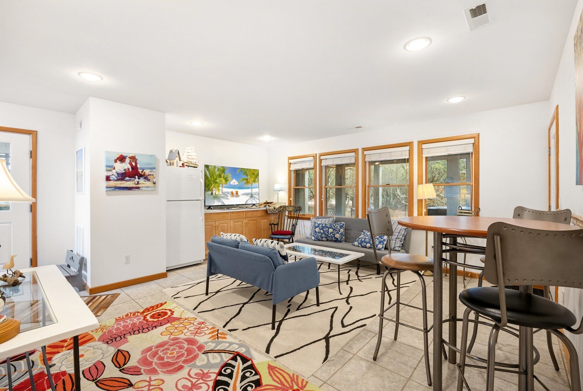 A modern kitchen with a refrigerator, a dining area with a table and chairs, and a living area with a sofa and a coffee table.