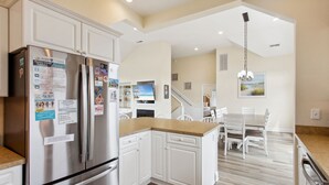Una cocina moderna con armarios blancos, electrodomésticos de acero inoxidable y encimera de madera.