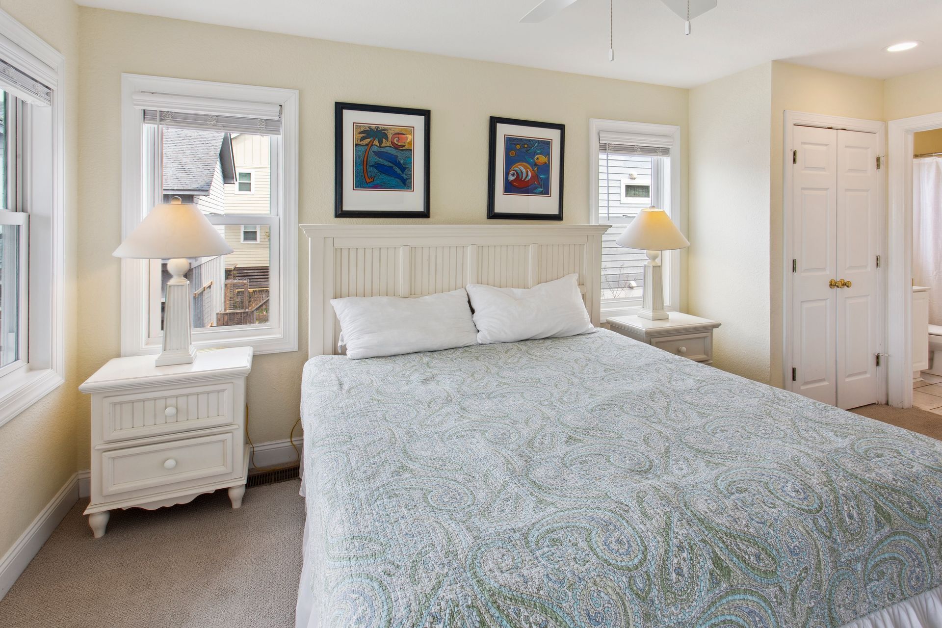 A bedroom with a bed, two nightstands, a window, and a door.