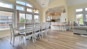 Un salón espacioso con comedor, ventanas amplias y una cocina al fondo.