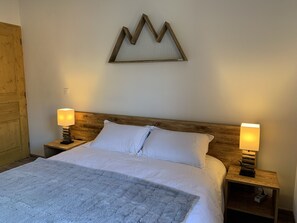 Een keurig opgemaakt bed met witte lakens, twee bedlampen en een houten hoofdbord.