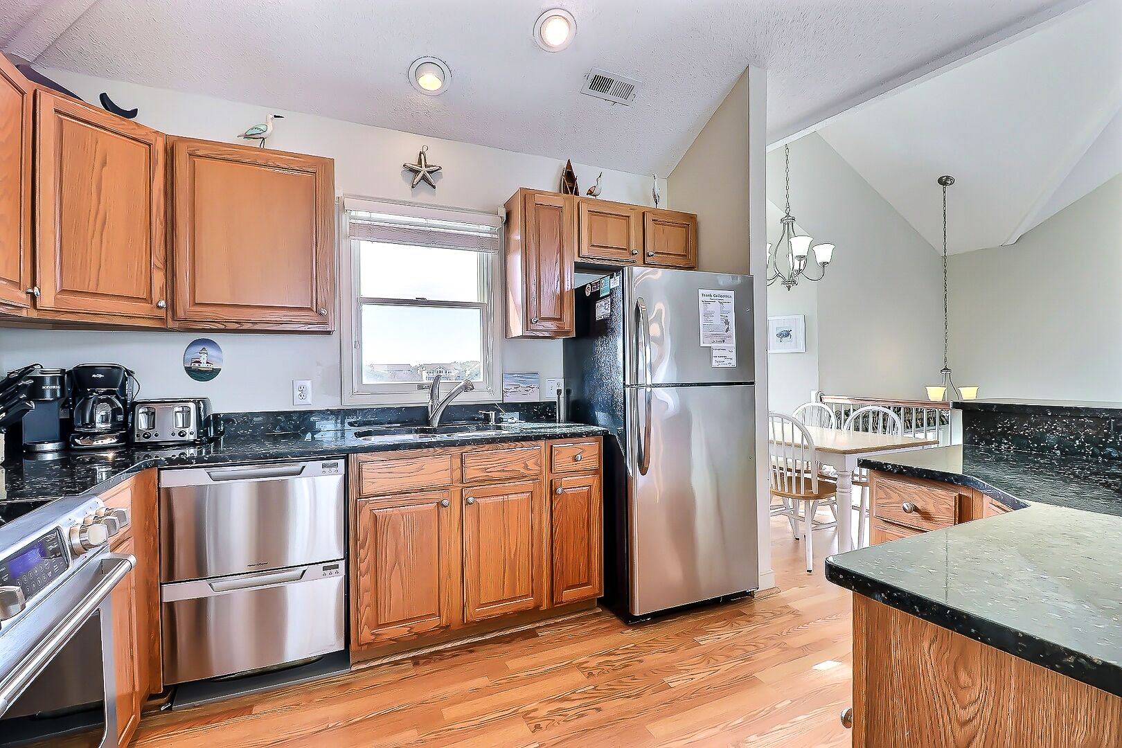 A modern kitchen with wooden cabinets, stainless steel appliances, and a large window.
