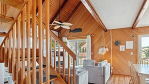 Een ruime woonkamer met een houten trap, een eettafel en een bank.