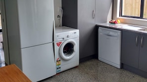 A compact kitchen with a washing machine, a refrigerator, and a dishwasher. - Omanu Beach Break - Walk across the road to the beach, close to golf (Mount Maunganui)