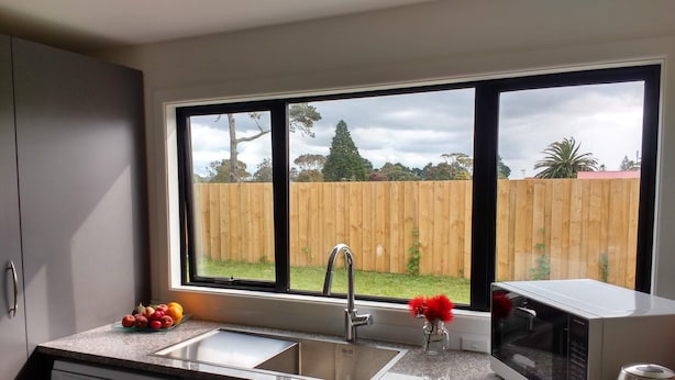 A kitchen with a window, a dishwasher, a sink, and a microwave. - Omanu Beach Break - Walk across the road to the beach, close to golf (Mount Maunganui)