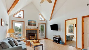 Una sala de estar amplia con chimenea, televisor y un ventanal grande.