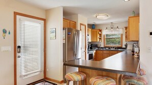 Una cocina moderna con armarios de madera, un refrigerador de acero inoxidable, un horno empotrado y una isla grande con taburetes de bar.
