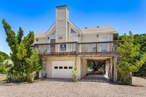 A two-story house with a covered garage, a balcony, and a sign indicating a vacation home. - Destiny: Pool, Hot Tub, Walk to Beach OBX (Corolla)