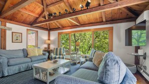 Un salon chaleureux avec des poutres en bois, de grandes fenêtres et des sièges confortables.