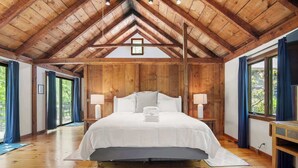 Une chambre à coucher en bois avec un grand lit, deux lampes de chevet et une vue par la fenêtre.