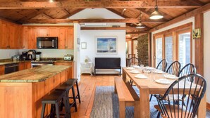 Une cuisine rustique avec des meubles en bois, un four à micro-ondes et un coin repas avec une table dressée pour quatre personnes.